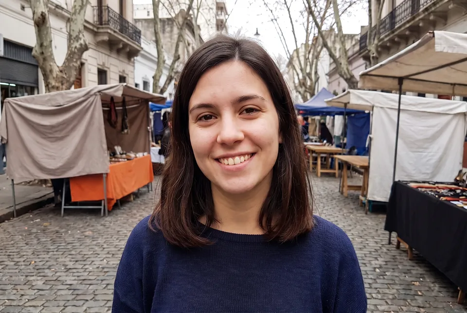 After: the same photo with both people gone and the acne cleared; her face, smile, hair and the street fair are unchanged.